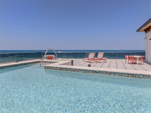 view of pool with a water view and a patio