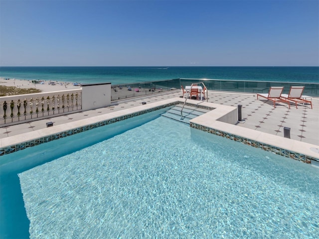 view of swimming pool with a water view and a beach view