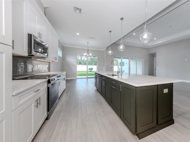 kitchen featuring appliances with stainless steel finishes, sink, an island with sink, white cabinetry, and pendant lighting