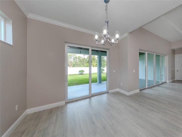 empty room featuring a notable chandelier, ornamental molding, and light hardwood / wood-style flooring