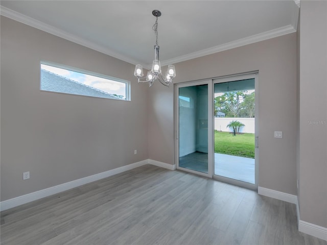 empty room featuring crown molding, light hardwood / wood-style flooring, a chandelier, and plenty of natural light