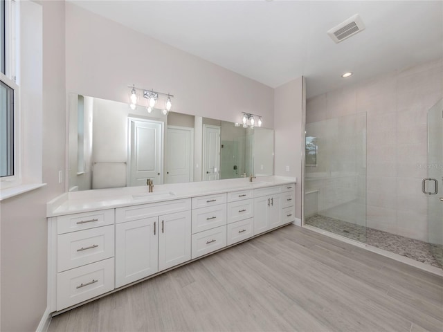 bathroom featuring vanity, a shower with shower door, and wood-type flooring