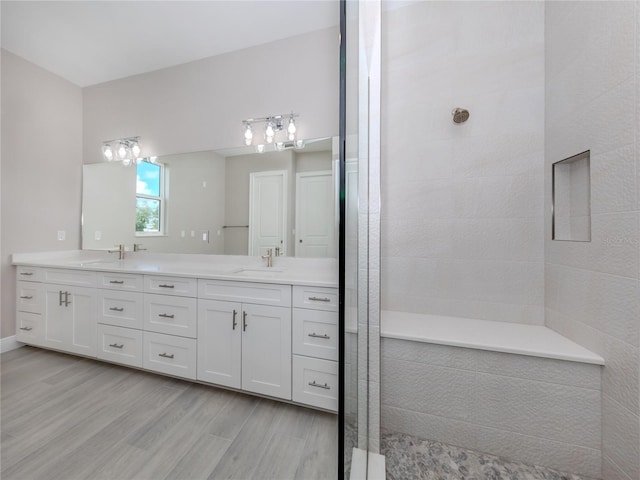 bathroom with vanity, wood-type flooring, and tiled shower