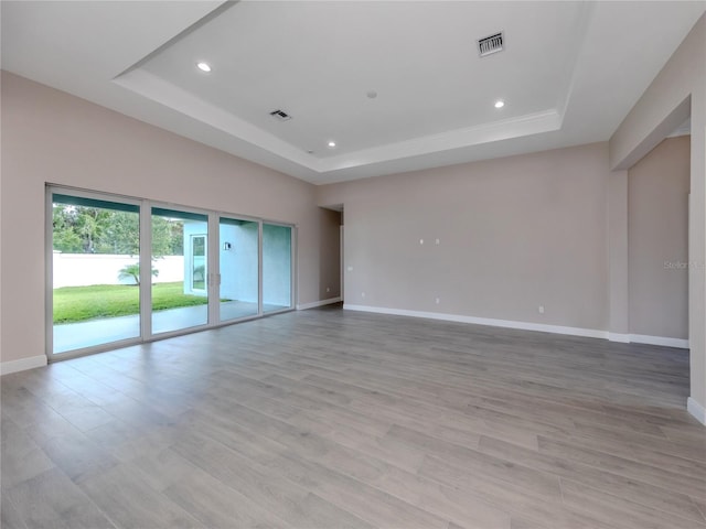 spare room with light hardwood / wood-style flooring and a tray ceiling