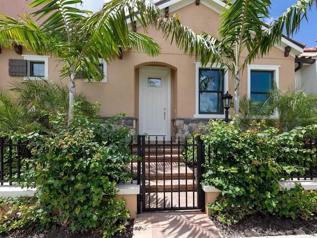 910 E Venice Ave, Venice, FL 34285 - property entrance featuring stone siding, a gate, stucco siding, and fence