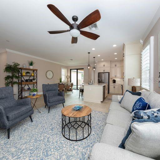 living room with ceiling fan, ornamental molding, and light tile patterned floors