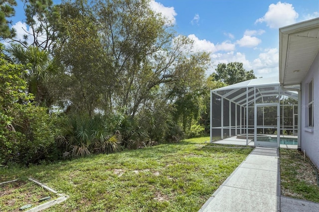 view of yard with glass enclosure and a patio area