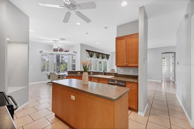 kitchen featuring sink, stainless steel dishwasher, ceiling fan, light tile patterned floors, and a kitchen island