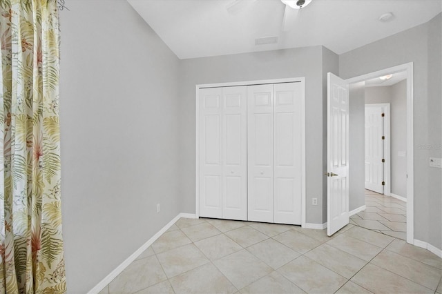 unfurnished bedroom with ceiling fan, a closet, and light tile patterned flooring