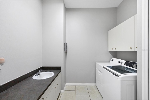 washroom featuring separate washer and dryer, sink, light tile patterned floors, and cabinets