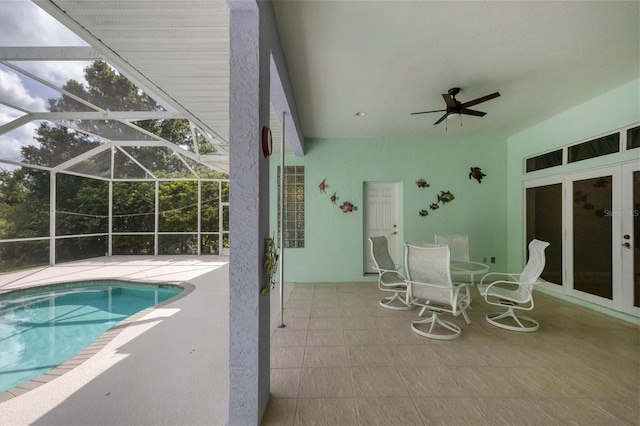 view of swimming pool with ceiling fan, a patio area, glass enclosure, and french doors