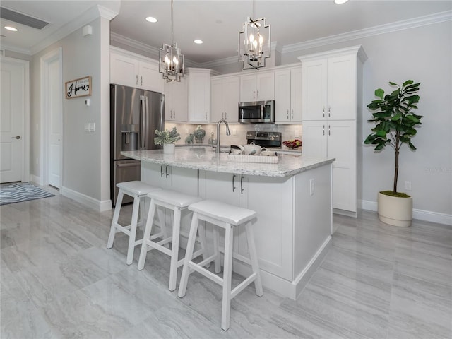 kitchen featuring white cabinetry, stainless steel appliances, decorative backsplash, decorative light fixtures, and a center island with sink