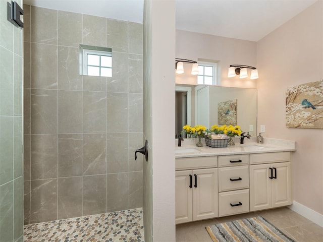 bathroom with tiled shower, a wealth of natural light, tile patterned flooring, and double vanity