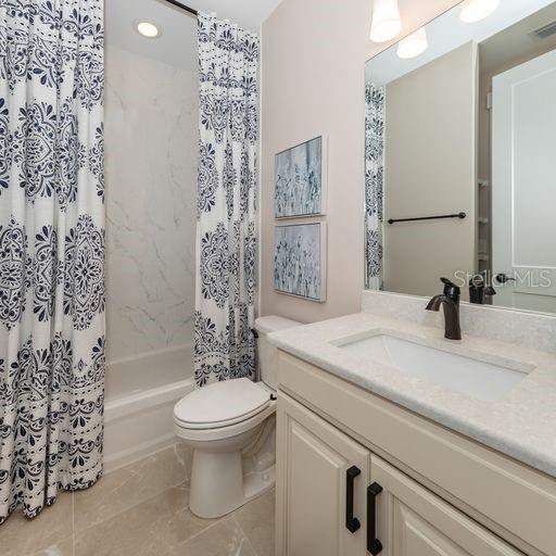 full bathroom with vanity, shower / bathtub combination with curtain, tile patterned flooring, and toilet