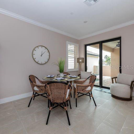 dining room with light tile patterned floors and ornamental molding