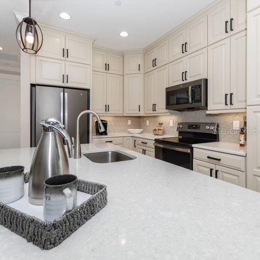 kitchen featuring stainless steel appliances, tasteful backsplash, sink, and pendant lighting