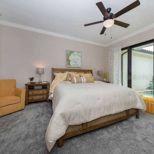 carpeted bedroom with ornamental molding and ceiling fan