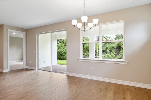 unfurnished room featuring light wood-style floors, baseboards, and a chandelier