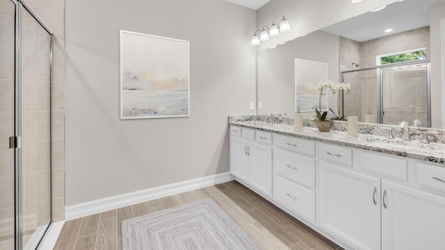 full bathroom featuring a stall shower, a sink, baseboards, and wood tiled floor