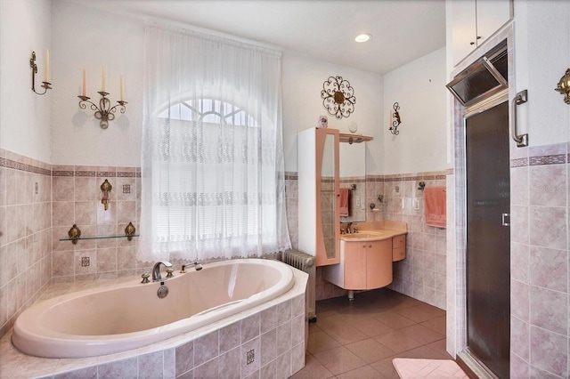 bathroom with tile patterned flooring, tiled tub, plenty of natural light, and vanity