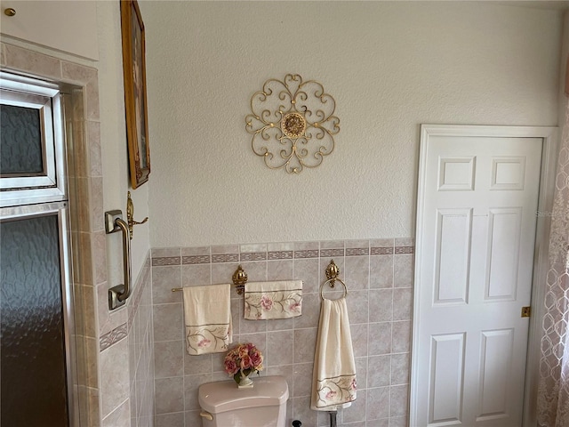 bathroom with toilet, tile walls, and walk in shower