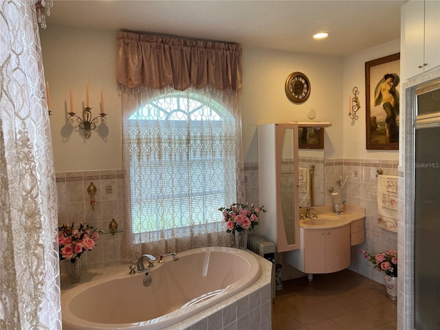 bathroom with vanity, tile walls, tile patterned floors, and tiled tub