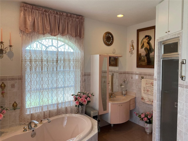 bathroom with a washtub, tile walls, vanity, and tile patterned flooring