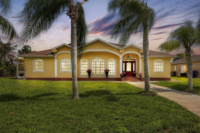 mediterranean / spanish-style home featuring a lawn and french doors