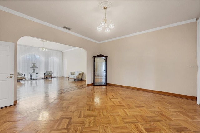 spare room with crown molding, an inviting chandelier, and light parquet floors