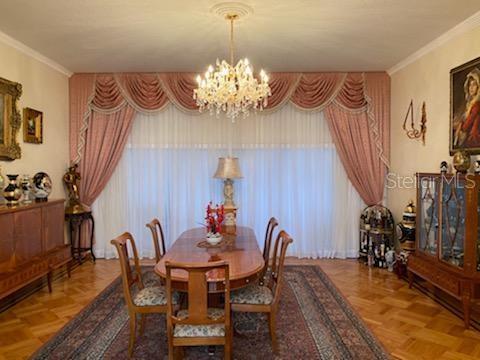 dining room featuring parquet floors, a healthy amount of sunlight, a chandelier, and ornamental molding