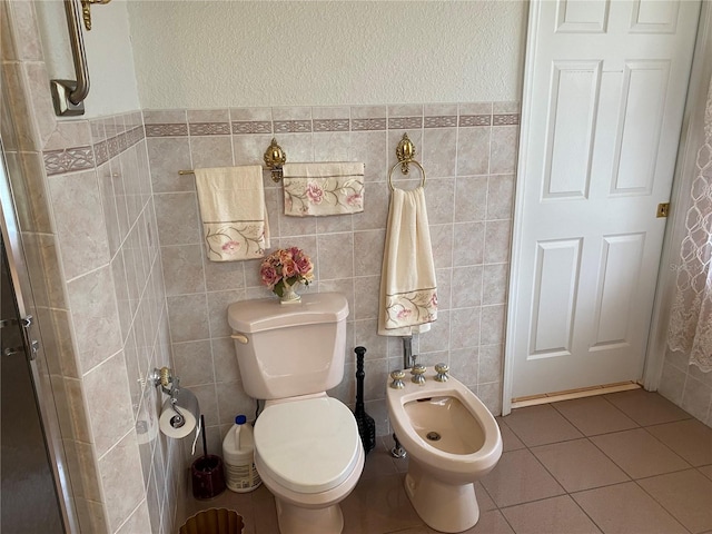 bathroom with toilet, tile walls, tile patterned flooring, and a bidet