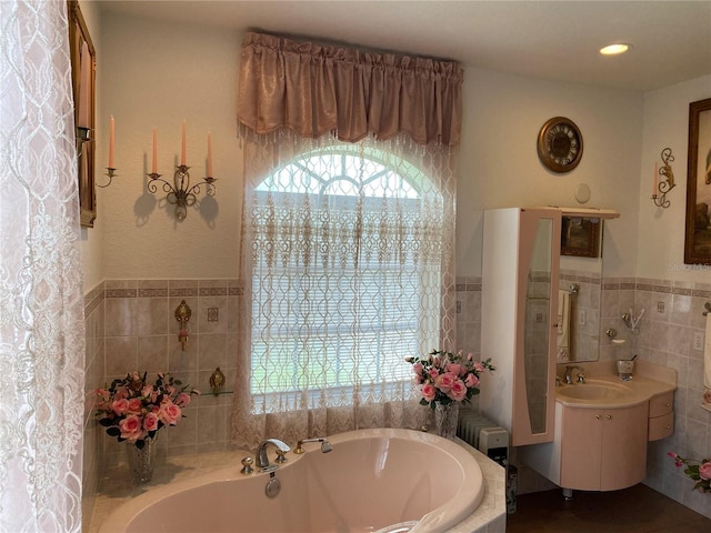 bathroom featuring tiled bath, tile walls, and vanity