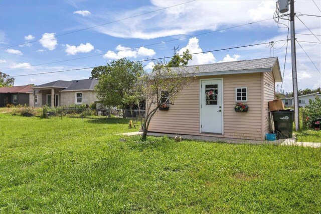 back of property with a lawn and a storage unit