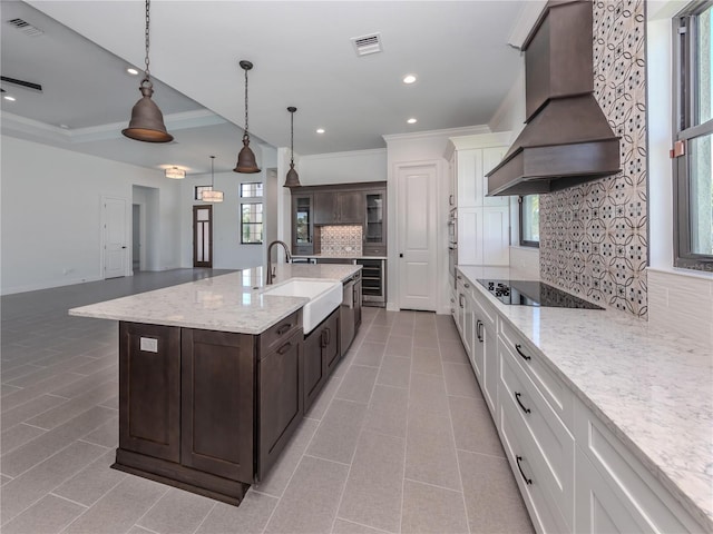 kitchen featuring backsplash, custom exhaust hood, black electric stovetop, and white cabinetry