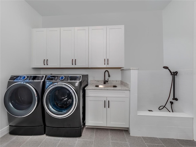 clothes washing area featuring washing machine and clothes dryer, cabinets, sink, and light tile flooring