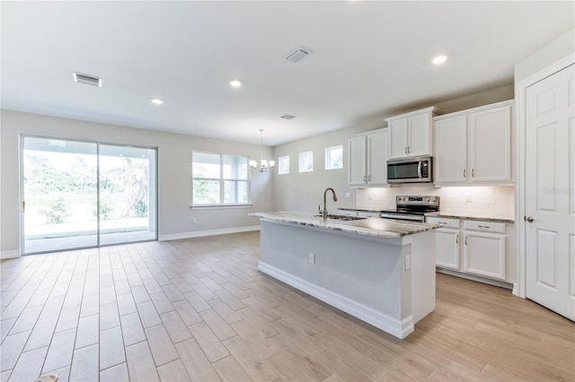 kitchen featuring white cabinets, a kitchen island with sink, sink, and appliances with stainless steel finishes