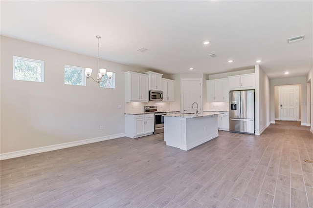 kitchen with a kitchen island with sink, white cabinets, sink, decorative light fixtures, and stainless steel appliances