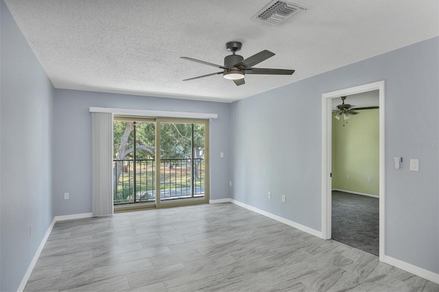 carpeted empty room featuring ceiling fan and a textured ceiling