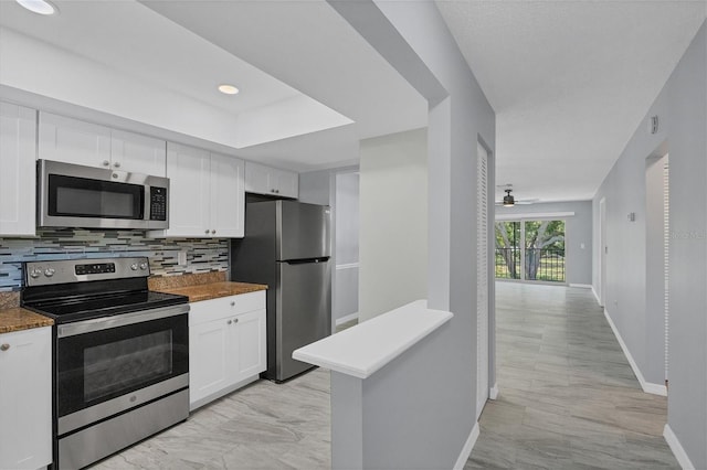 kitchen with stainless steel appliances, light tile floors, ceiling fan, white cabinets, and backsplash