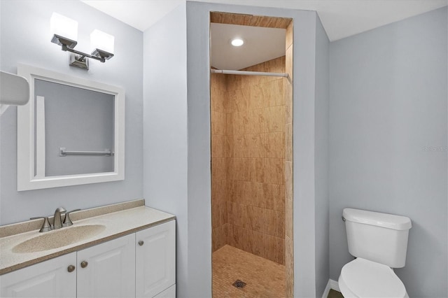 bathroom with vanity, a tile shower, and toilet