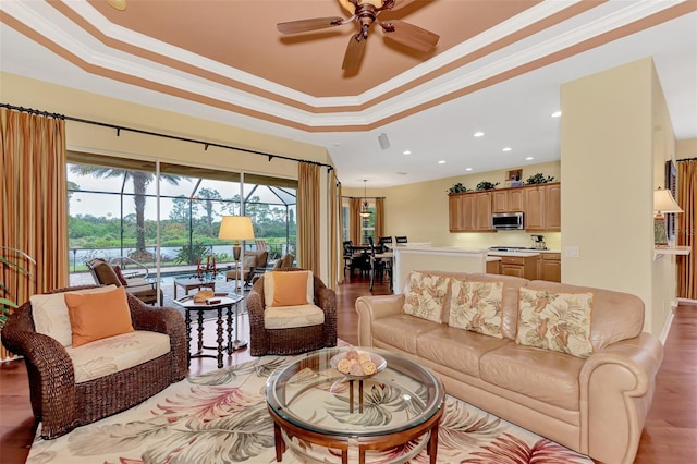 living room with hardwood / wood-style flooring, a raised ceiling, ceiling fan, and crown molding