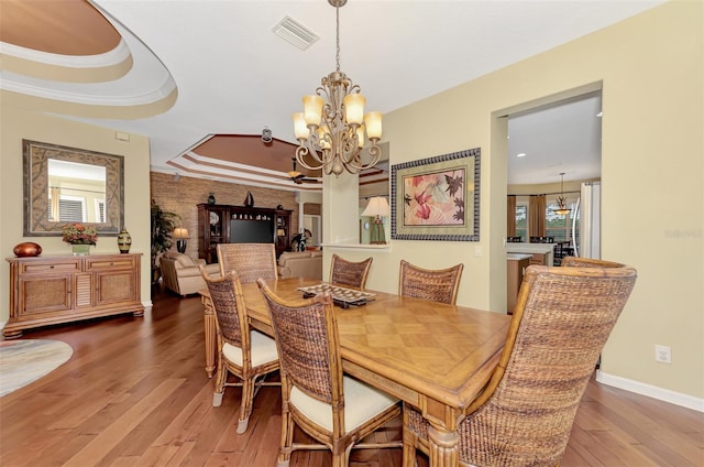 dining room featuring a chandelier, hardwood / wood-style flooring, a raised ceiling, and crown molding