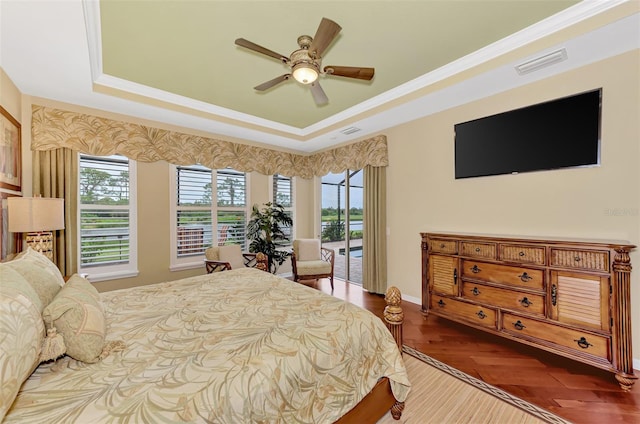 bedroom with a raised ceiling, multiple windows, ceiling fan, and crown molding