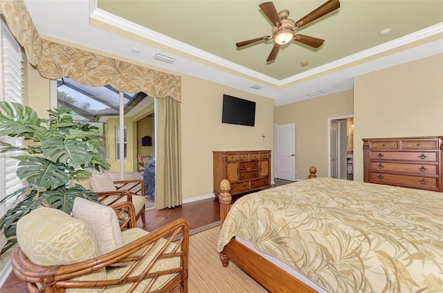 bedroom with hardwood / wood-style floors, a raised ceiling, ceiling fan, and crown molding