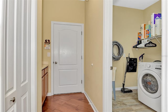 clothes washing area featuring washer / clothes dryer and light hardwood / wood-style flooring