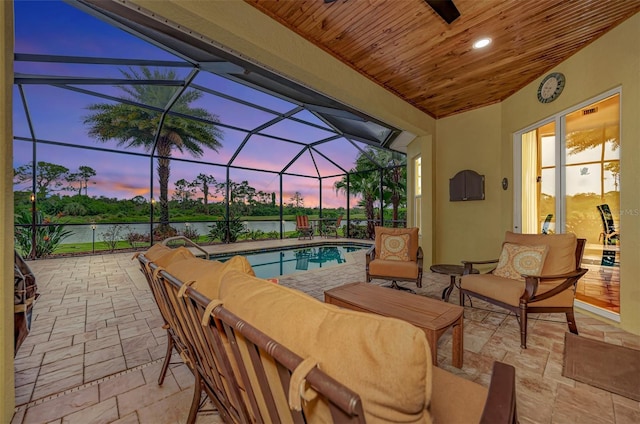 patio terrace at dusk featuring outdoor lounge area, a lanai, and a water view