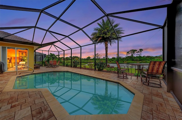 pool at dusk with a lanai and a patio