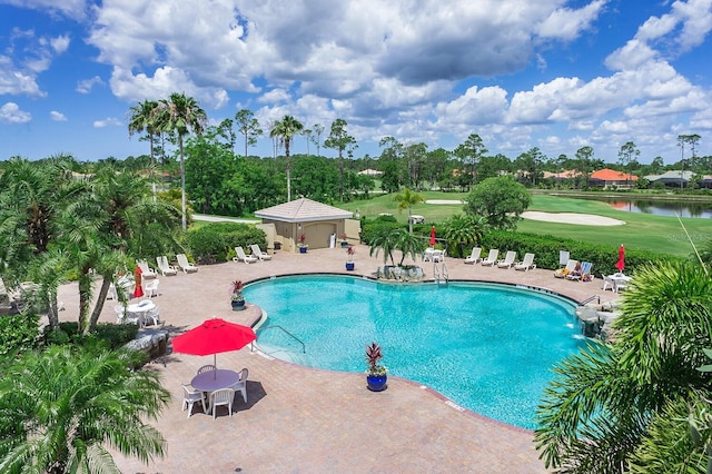 view of pool with a lawn, a water view, and a patio