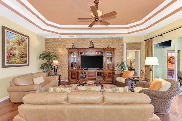 living room with a tray ceiling, ornate columns, ceiling fan, and crown molding