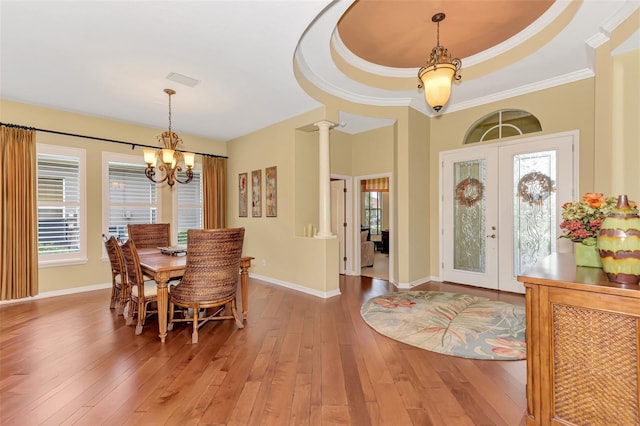 dining room with hardwood / wood-style floors, french doors, ornate columns, a wealth of natural light, and a tray ceiling